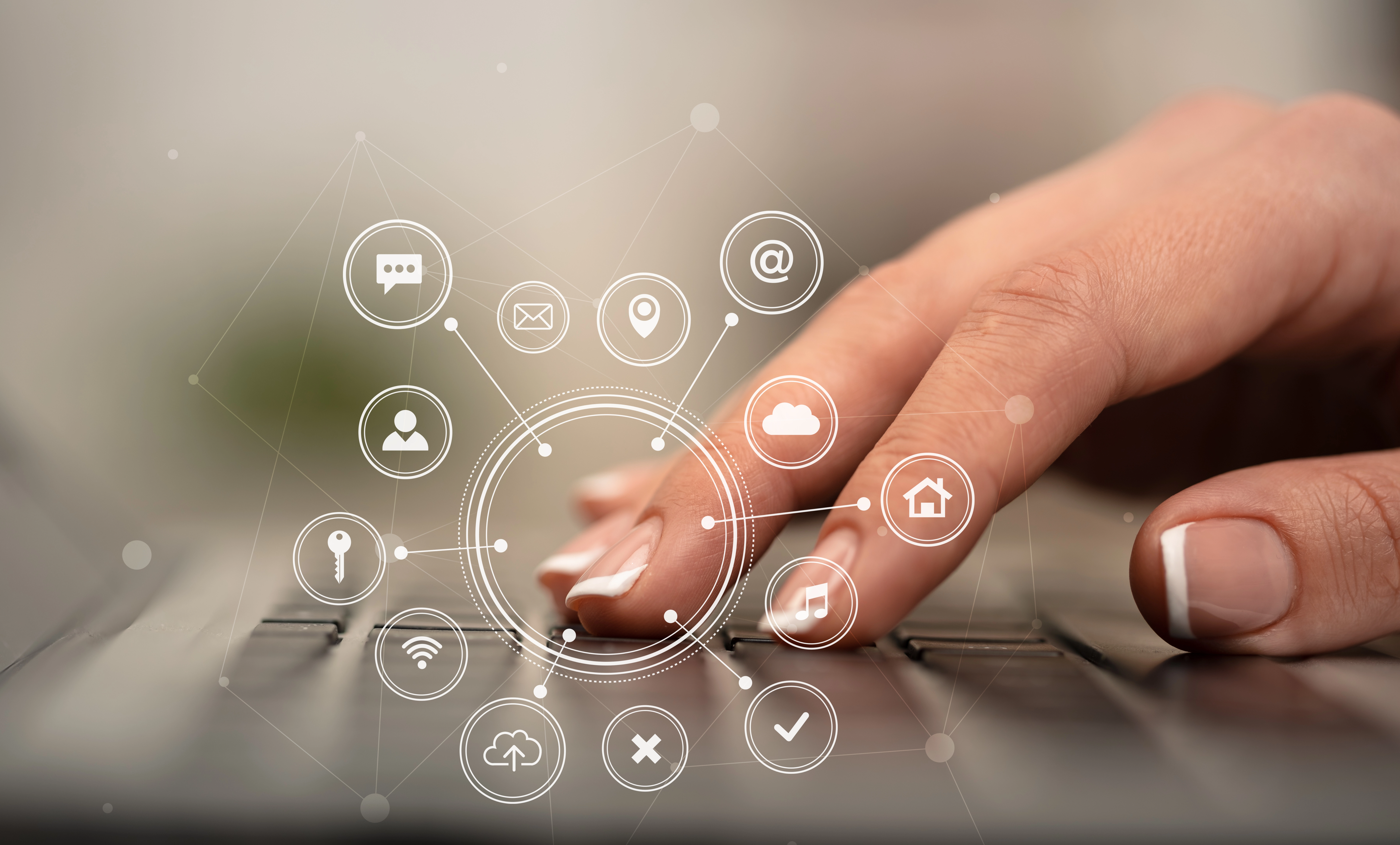 A hand typing on a laptop with connected app icons floating above the keys
